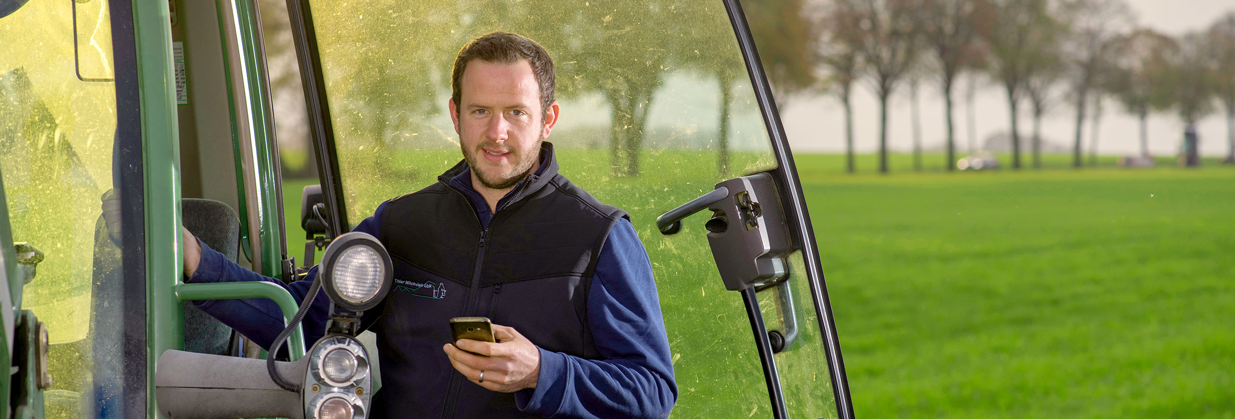 Landwirt mit Traktor und Handy auf Acker